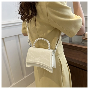 Dettaglio della mini borsa bianca curva con manico in perle e trama in pelle pieghettata