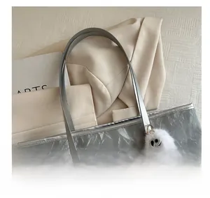 Détail du cabas argenté métallisé avec anses confortables et breloque en peluche douce