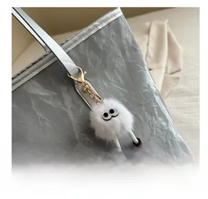 Gros plan d'une breloque en peluche blanche avec bottes sur un sac fourre-tout argenté