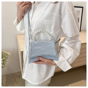 Dettaglio mini borsa azzurra in pelle verniciata a pieghe con elegante manico di perle