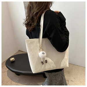 Détail du sac fourre-tout crème avec texture froissée et breloque pelucheuse mignonne