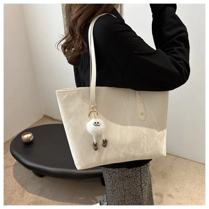 Détail du grand sac cabas crème avec texture plissée et charmant pendentif monstre en peluche