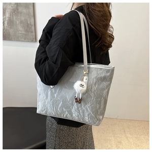 Détail d'un sac cabas argenté avec texture métallique plissée et breloque en peluche