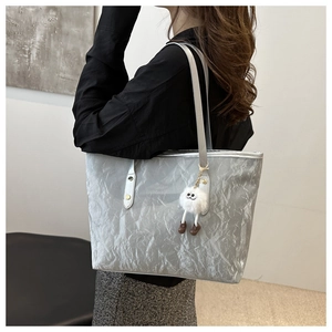 Sac fourre-tout argenté chic à texture froissée porté à l'épaule avec charme en peluche