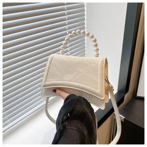 Dettaglio borsa a mano bianco crema lucida con elegante manico in grandi perle tonde