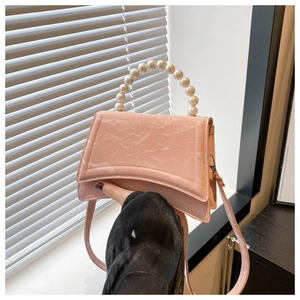 Dettaglio della borsa a mano rosa plissettata con manico di perle e base dal design curvo