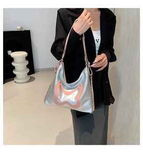Silver shoulder bag detail with pink butterfly patch and metallic chain strap
