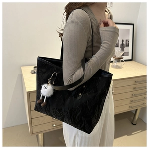 Vue détaillée du sac cabas noir avec pendentif peluche et rivets sur la bandoulière