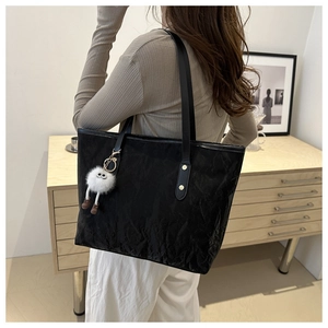 Grand sac cabas noir texturé avec breloque monstre en peluche porté par le mannequin