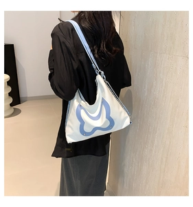 White tote bag with blue butterfly detail and metal chain strap shown on a model