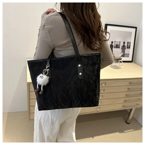Sac fourre-tout noir texturé avec breloque en peluche porté à l'épaule pour le style