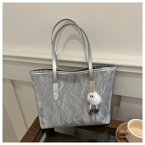 Gros plan du sac cabas argenté métallisé avec texture froissée et breloque peluche