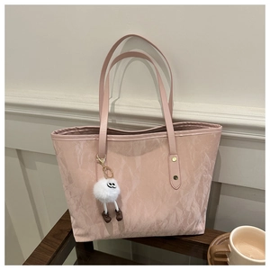 Détail du sac cabas rose avec texture froissée et porte-clés monstre en peluche blanc