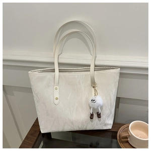 Détail d'un grand sac fourre-tout blanc cassé avec surface texturée et pendentif peluche