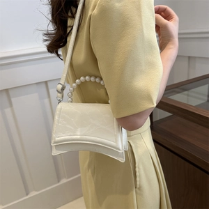 Borsa a mano minimalista crema con manico di perle e texture indossata da modella