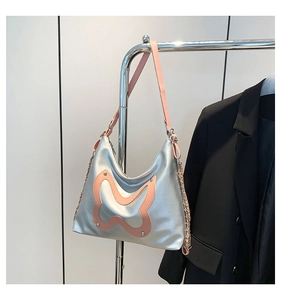 Close-up of silver tote bag with pink butterfly patch and metal rivet details