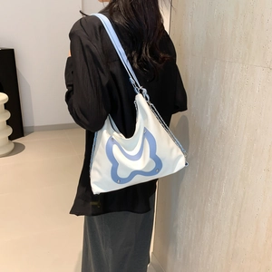 White minimalist tote bag with blue butterfly detail and chain strap worn by a model