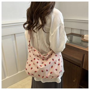 Gros plan d'un sac cabas en velours côtelé rose à motifs fraises sur un mannequin