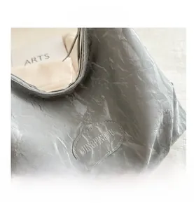 Macro shot of silver-gray bag with textured pleats and an oval leather brand patch