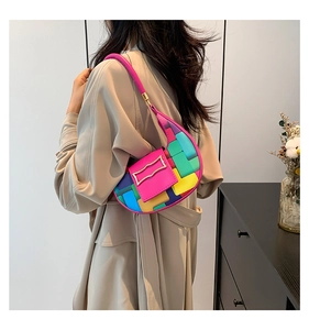 Side view of a colorful woven crescent underarm bag worn with a beige trench coat