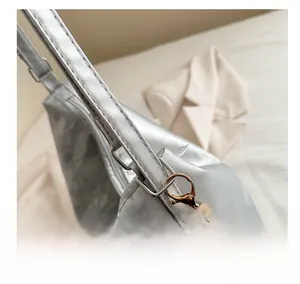 Detail of light gold metal hook on silver leather tote bag with crinkle texture