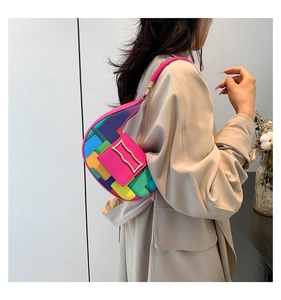 Side view of a colorful geometric patchwork underarm bag worn by a model in a minimal setting