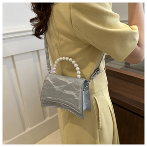 Borsa a tracolla argento con manico di perle e base curva indossata da una modella