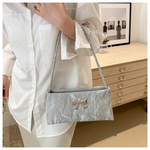 Dettaglio borsa a pieghe azzurro chiaro con fiocco argento e tracolla sottile elegante
