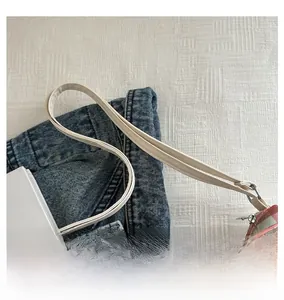 Close-up of adjustable cream leather strap and silver buckle on plaid fabric tote bag
