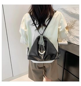 Detail of black triangular backpack with silver chains and pearls worn on the back