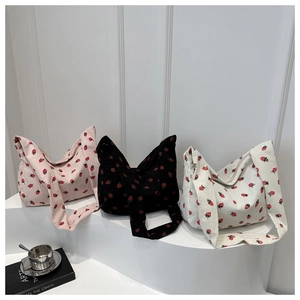 Gros plan sur le motif fraise des sacs cabas en velours côtelé rose, noir et beige
