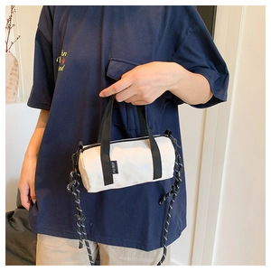 Détail d'un sac cylindrique en nylon blanc avec sangles contrastées et patch de marque