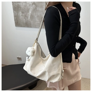 Detail of cream white nylon tote bag featuring a plush cloud charm and brand patch