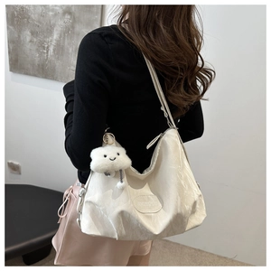 Detail of off-white hobo tote bag with pleated texture and plush cloud pendant charm