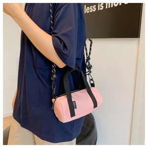Détail du sac bandoulière cylindrique rose en toile avec double sangle et étiquette logo
