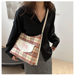 Detail of plaid tote bag featuring a pink bow embroidery and white leather pocket flap