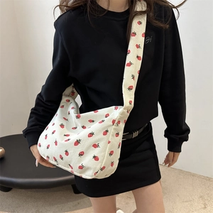 Sac cabas en velours côtelé blanc à imprimé fraises rouges porté par un mannequin