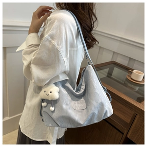 Detail of light blue pleated shoulder bag with plush cloud charm and metallic logo tag