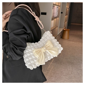 Detail der weißen Plissee-Schultertasche mit beiger Satinschleife und pinkem Gurt