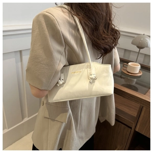 Close-up of cream shoulder bag with elegant knotted strap detail and ruched leather texture