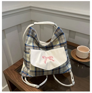 Detail of tartan plaid backpack with white leather pocket and pink ribbon embroidery