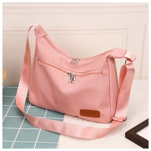 Detail of pink nylon shoulder bag showing the zipper pocket and wide fabric strap