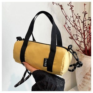 Détail d'un sac à main cylindrique jaune en nylon avec poignées noires et bandoulière