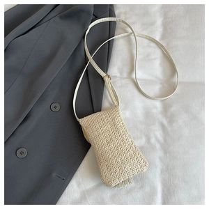 Detailed view of cream woven straw mobile phone bag with long tassels and slim shoulder strap