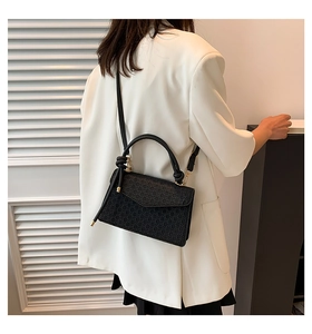 Detail of the woven texture and knotted handle on this black crossbody square bag