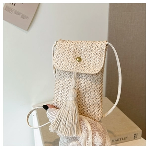 Detail of hand-woven straw crossbody phone bag featuring long fringe and gold snap button