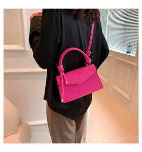 Detail showing flamingo pink woven texture and unique knotted handle on a handbag