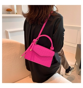 Close-up of bright pink woven texture handbag with knotted handle and metal buckle