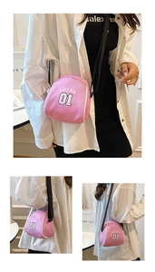 Detail of pink canvas crossbody bag featuring athletic white letter print and black strap