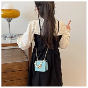 Détail d'un sac pailleté pour enfant avec poignée en perles et pendentif cœur doré